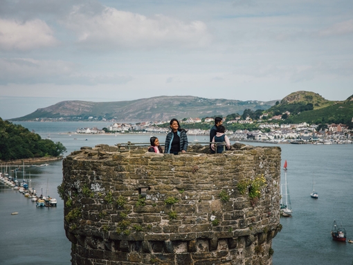 Family on top of a castle enjoying river views with boats docked and hills in the distance
