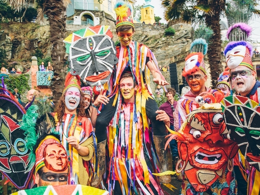 Eine Gruppe von Darstellern in farbenfrohen Kostümen mit bemalten Gesichtern