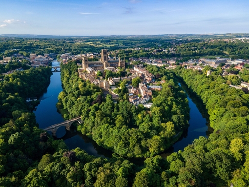 An elevated view of a Cathedral set amongst trees and a river