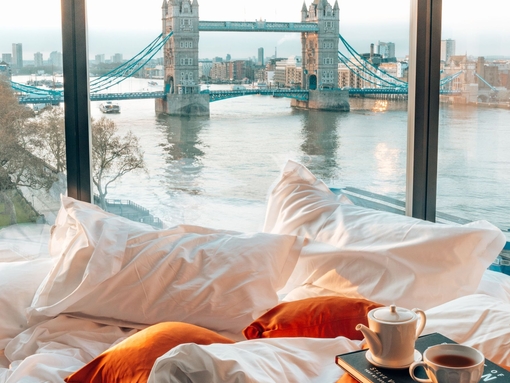 An unmade bed with views of Tower Bridge from window