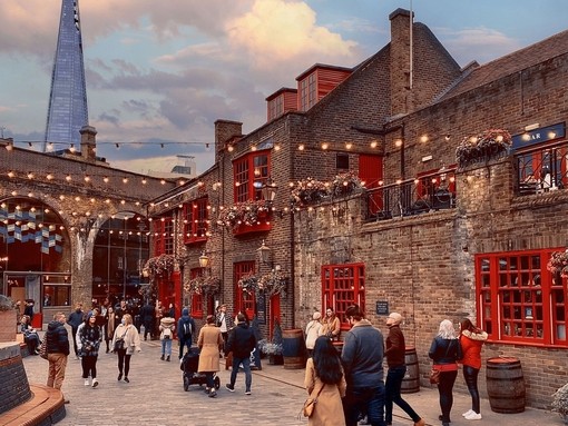 People walking past a pub, in Southwark with the Shard building in the distance