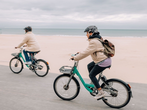 Two people cycling past Bournemouth's seafront.