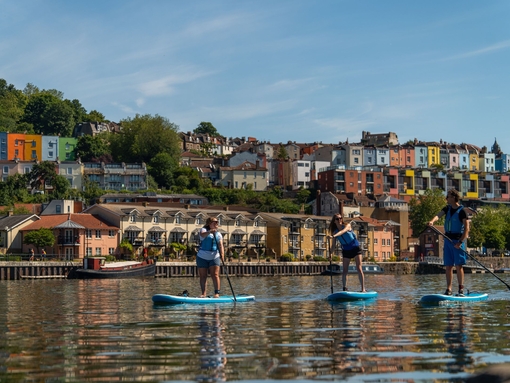 People paddleboarding on the river with the City of Bristol beyond