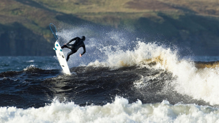 A surfer riding waves off the coast of the UK