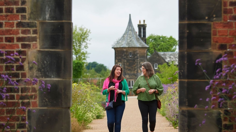 Two women walking toward archway, RHS Bridgewater