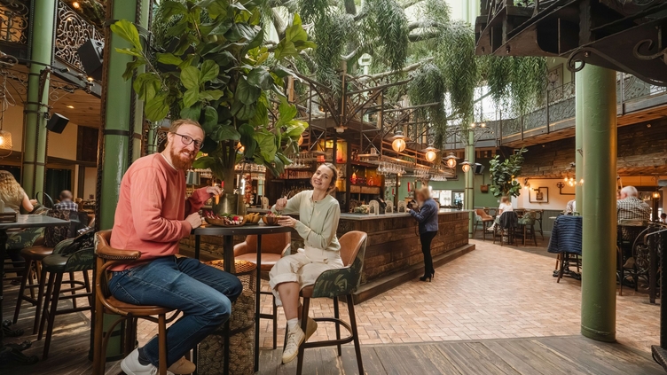 A man and a woman enjoying food and drinks at a high end two storey city wine bar and restaurant.