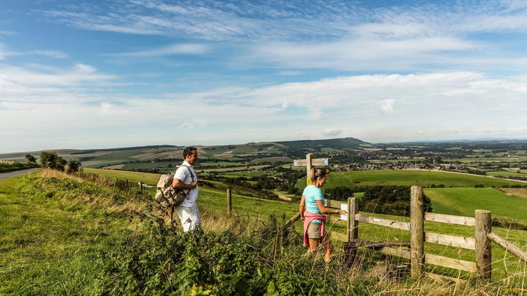 Walkers on path through fields near a direction signpost and a style
