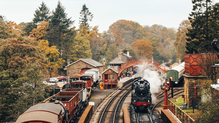 Steam train on train tracks and old-fashioned carriages at Goathland Railway Station