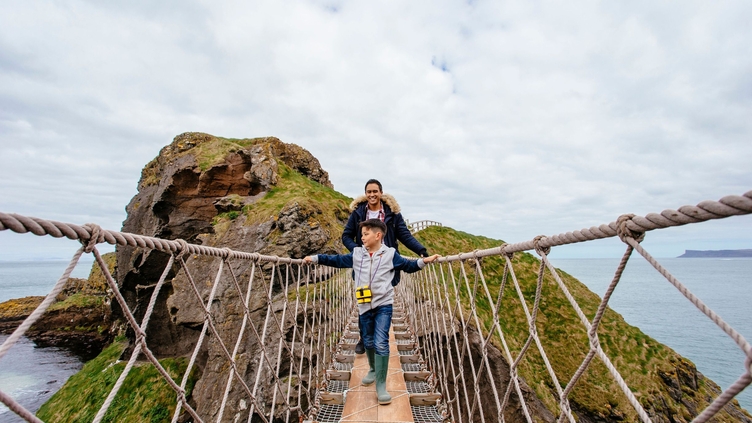 Man and child crossing a long rope bridge 
