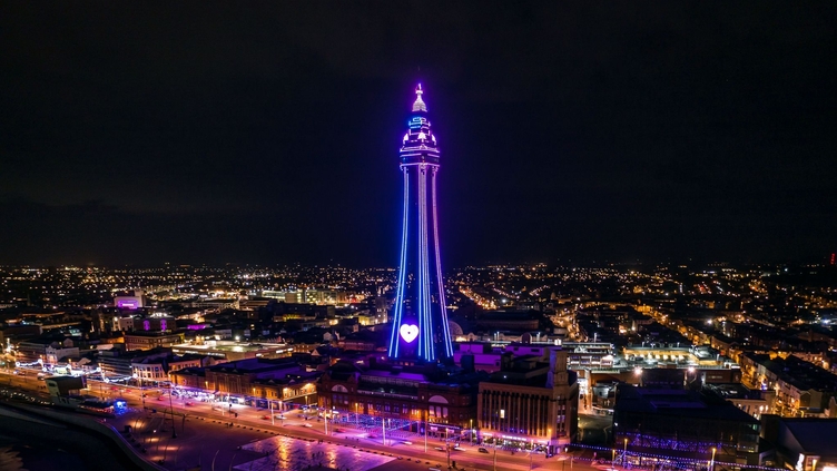Seaside town at night with tower lit up.