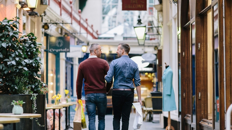 A gay couple, with arms linked, shopping indoors