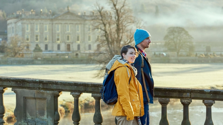 A young couple standing at the balustrade of a stone bridge
