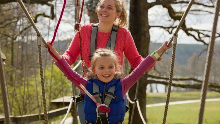 Girl and woman balancing on an elevated hanging walkway