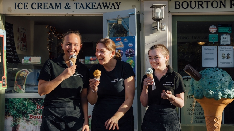 Three smiling woman standing outside ice cream parlour