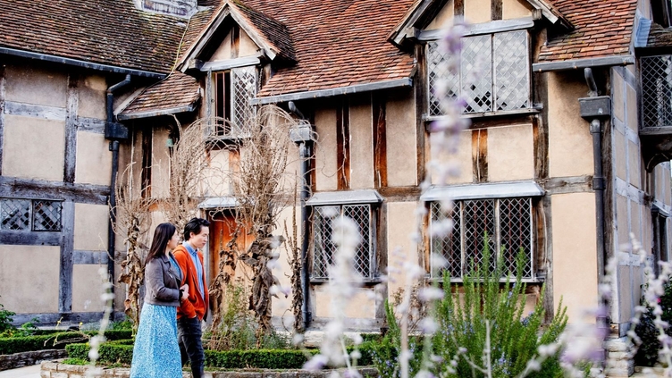 Couple walking around the exterior of Shakespeare's Birthplace, Stratford-upon-Avon, Warwickshire, England