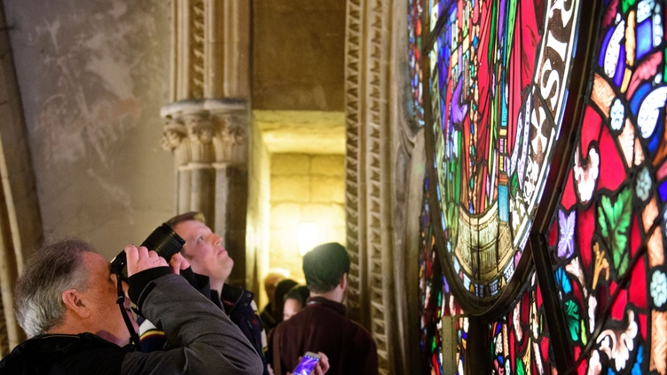A tour group on a tour of Lincoln Cathedral, looking at a stained glass window