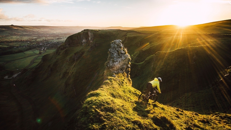 Cyclist riding down a steep glassy slope at sunset