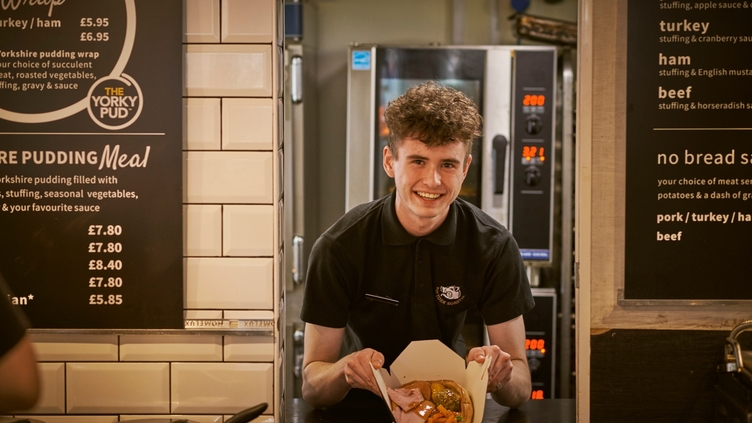 Young man standing behind the counter of a restaurant