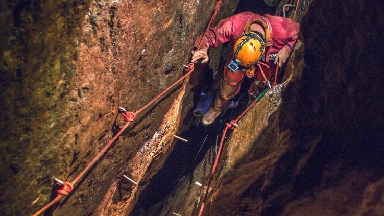 A man exploring through a cave system at Cornwall Underground Adventures