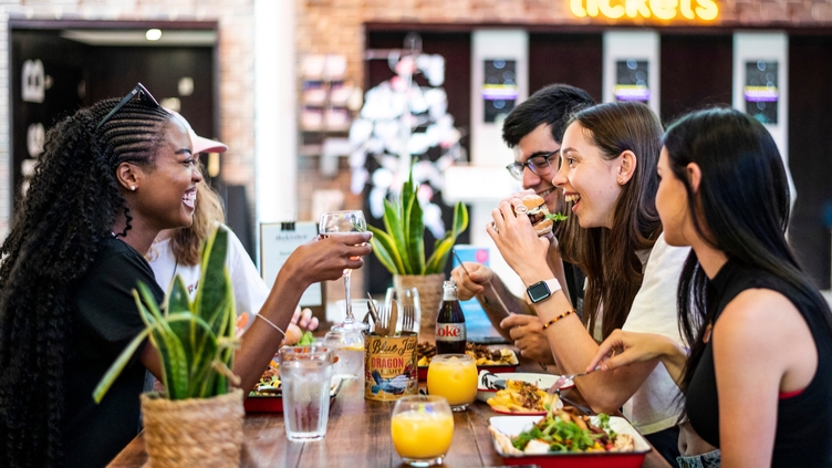 A group of people sitting on a bench eating food at the Storyhouse in Chester