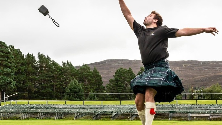 Hombre con falda escocesa lanzando pesas en Braemar Gathering, Escocia