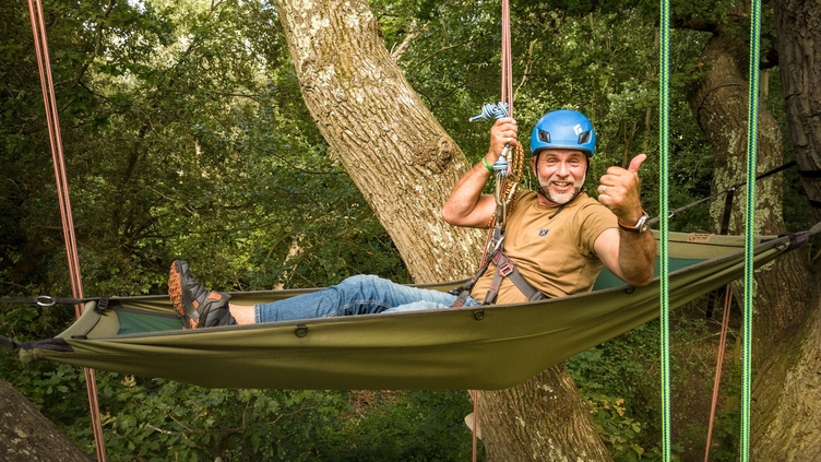 Man hanging from trees in hammock