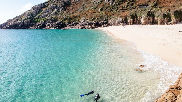 People scuba diving in sea off the coast. Calm seas