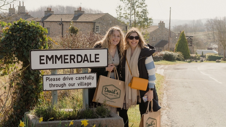 Two people posing outside the Emmerdale sign on a tour