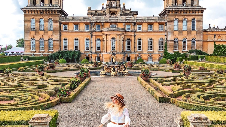 Woman walking in Blenheim Palace gardens surrounded by greenery