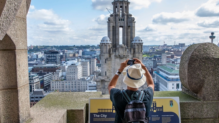 Gentleman photographing the tower in the skyline from the roof of the Royal Liver Building 360, Merseyside. Silver winner of the Small Visitor Attraction of the Year in the VisitEngland Awards for Excellence 2022
