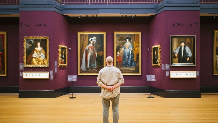 Rear view of man standing looking at portraits in a gallery