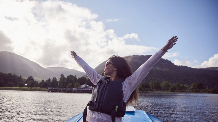 Woman with outstretched arms on a boat on the lake