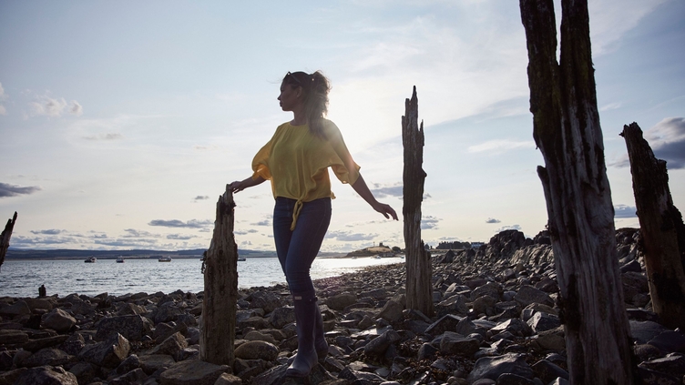 Woman balancing on rocks in between old stakes