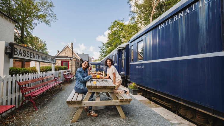 Mother and son having afternoon tea on the platform next to a heritage replica train.