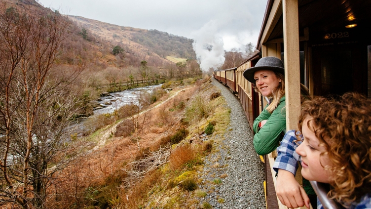 Woman and boy leaning out of window of steam train