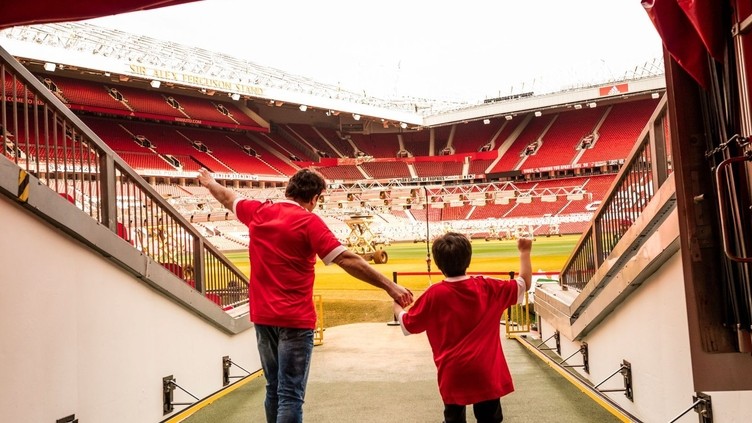A man and boy in stadium tunnel looking out to pitch