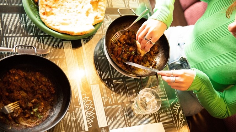 Woman sitting at table eating a curry