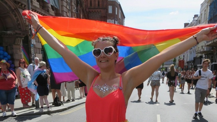 Mujer ondeando la bandera arco iris durante un acto del Orgullo