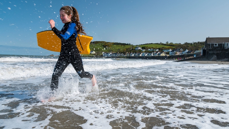 Girl running in the water with her surfboard