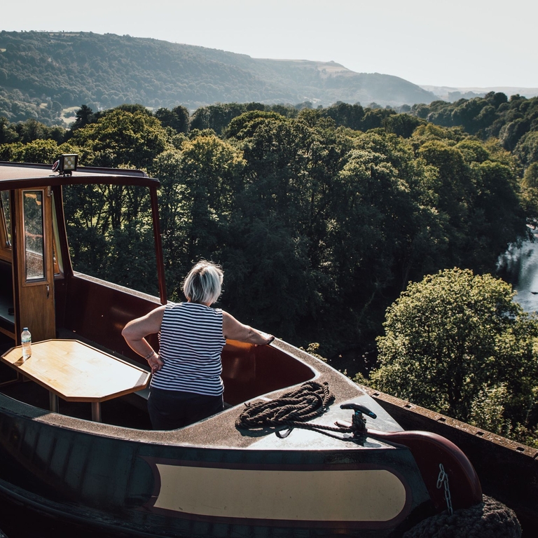 A woman in a barge crossing over an aqueduct.
