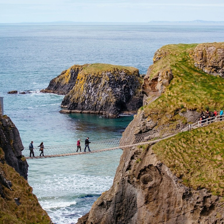 Vue lointaine de personnes traversant un pont de corde au-dessus de la mer