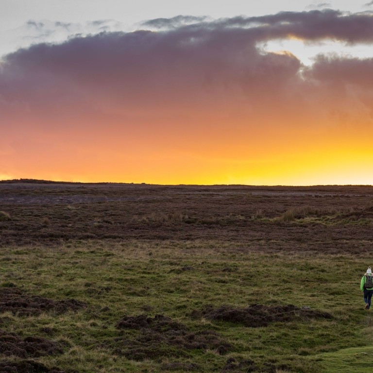 Two friends walking towards he sunset over the hill