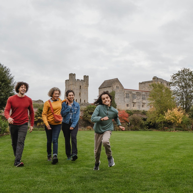 Family walking through a garden with ruins of a castle in the background
