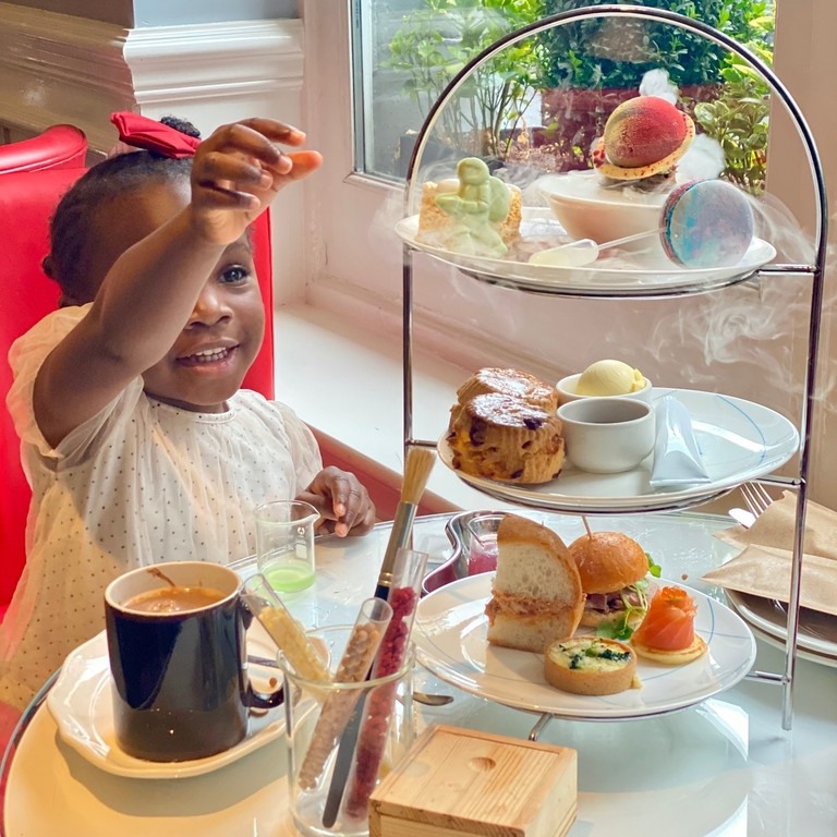 Child smiling and reaching for cake at an afternoon tea