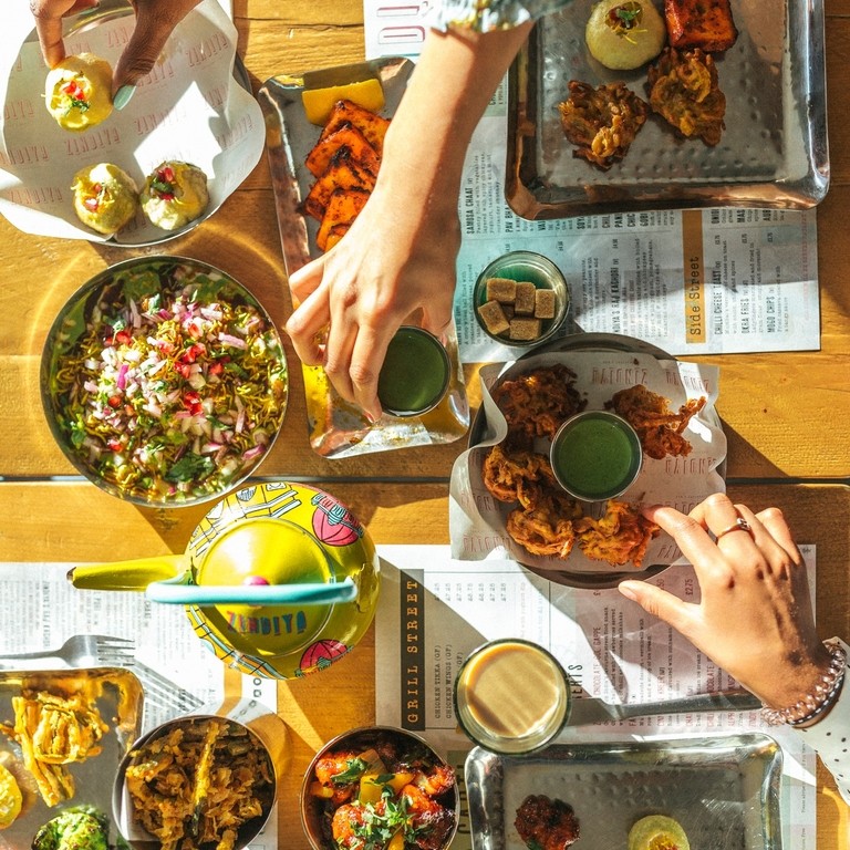 Hands picking up Indian food from a seclection of plates