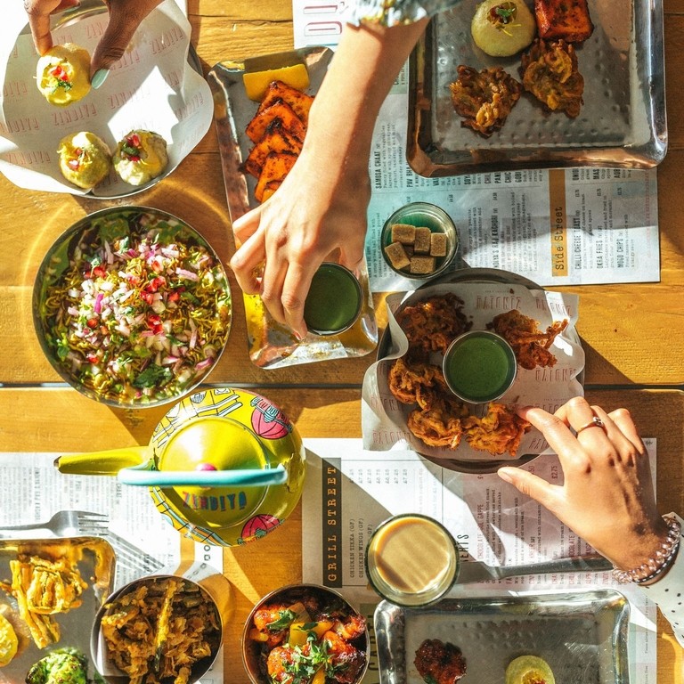 Hands picking up Indian food from a seclection of plates