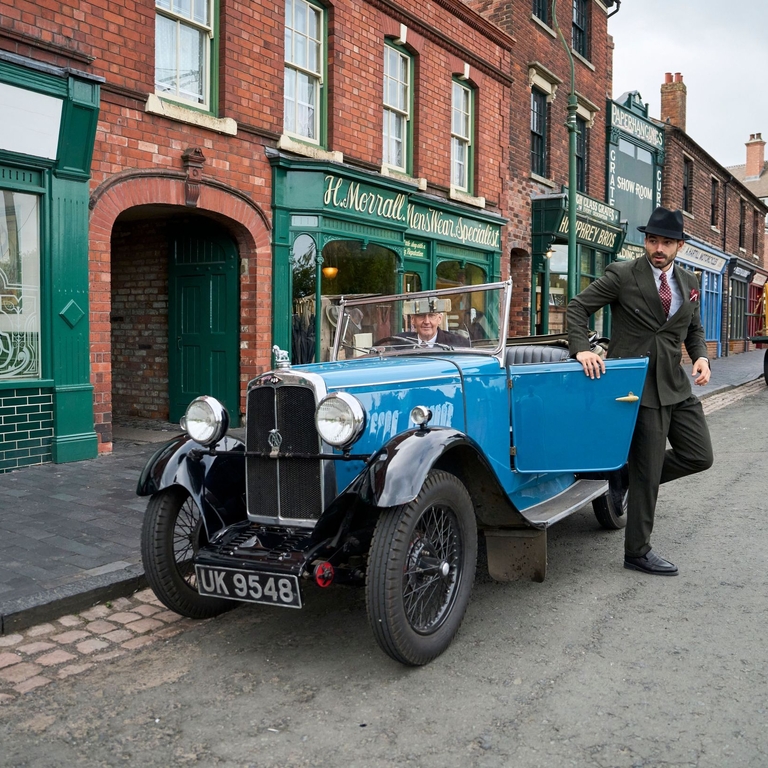 A man exiting a vintage car at a living museum