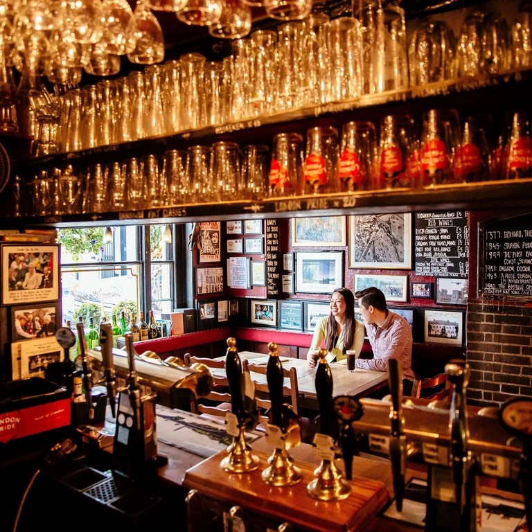 A young couple sat at a table. View from behind bar
