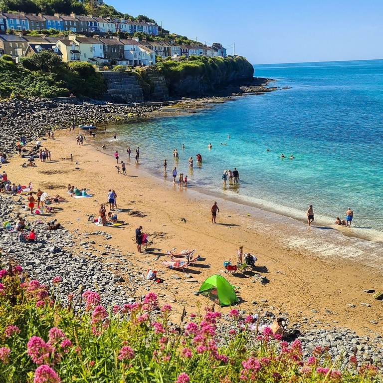 View of a bay with sandy beach and turquoise water with people