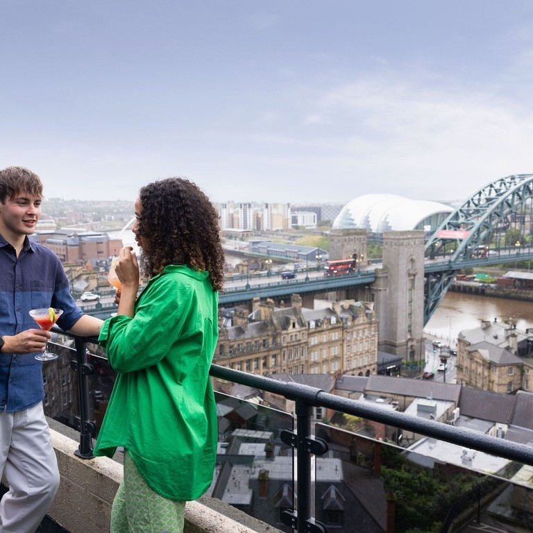 Two friends enjoy a cocktail at Above, a bar overlooking Newcastle upon Tyne city centre.